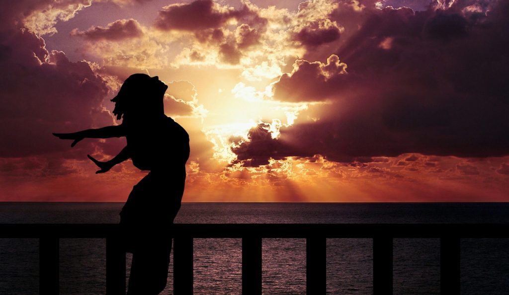 Woman with her hands spread behind her back as wings with ocean sinking in sunset on the background. Empowerment, freedom, hapiness, joy of love tWoman with hands spread behind back as wings with ocean sinking in sunset in background representing empowerment, freedom, happiness, joy of life which can be achieved by breath work.hat could be achieved through breathwork.