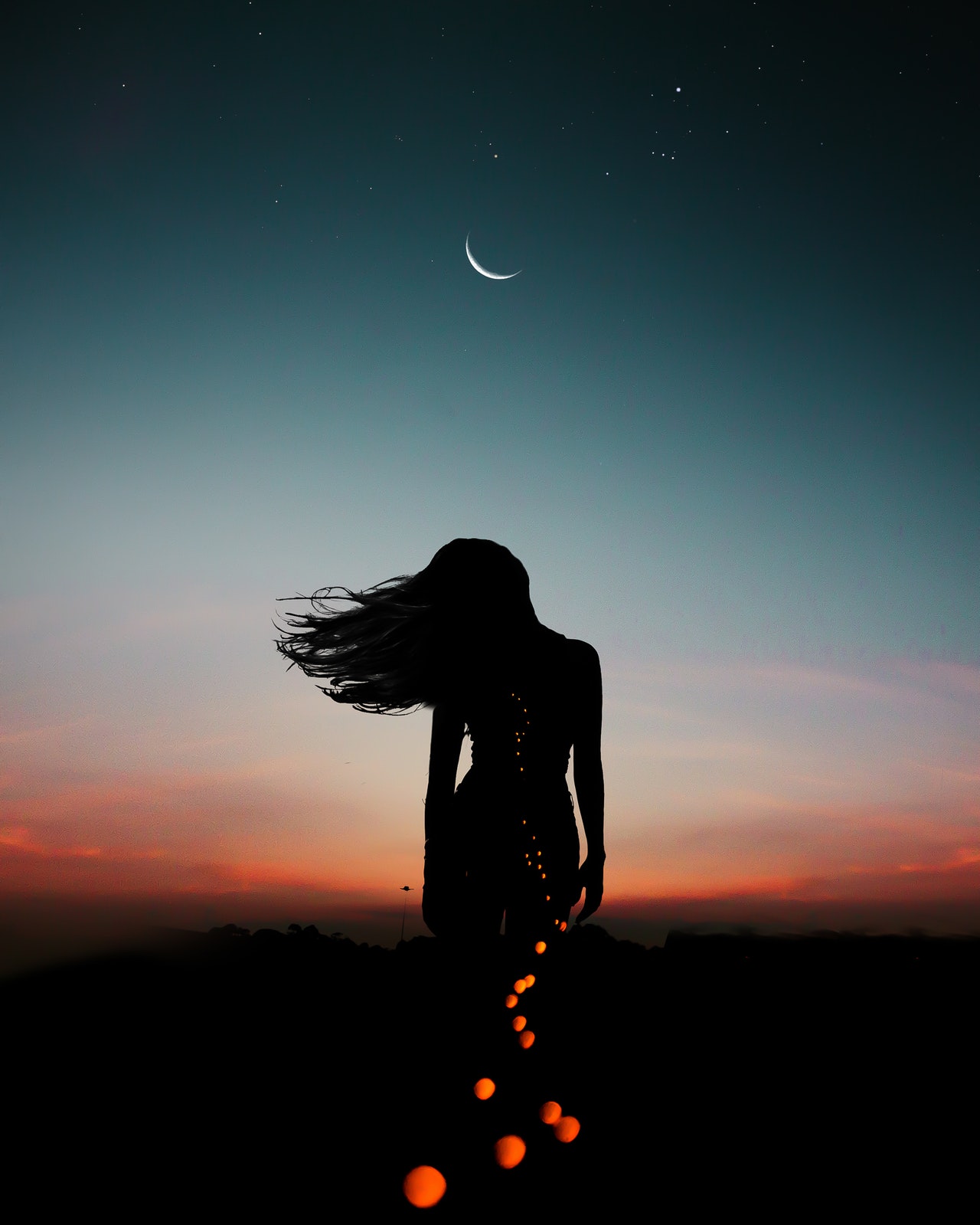Woman standing in the night under the new moon - freedom, spirituality, liberation